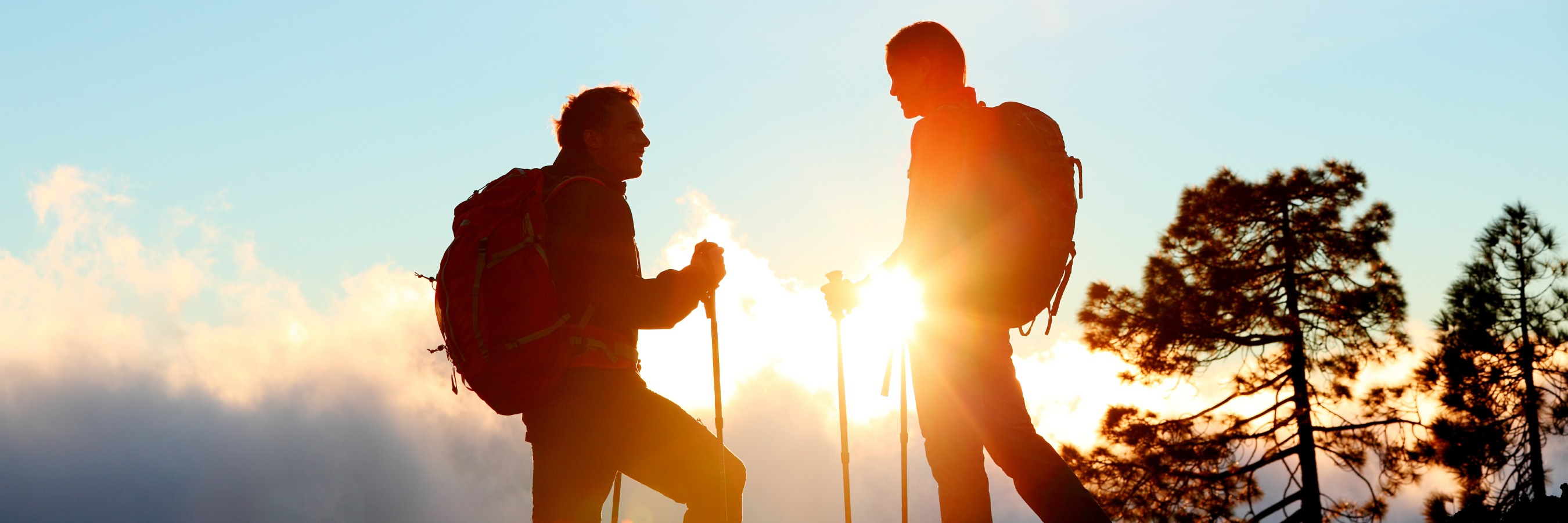 Two hikers silhouetted standing and talking together