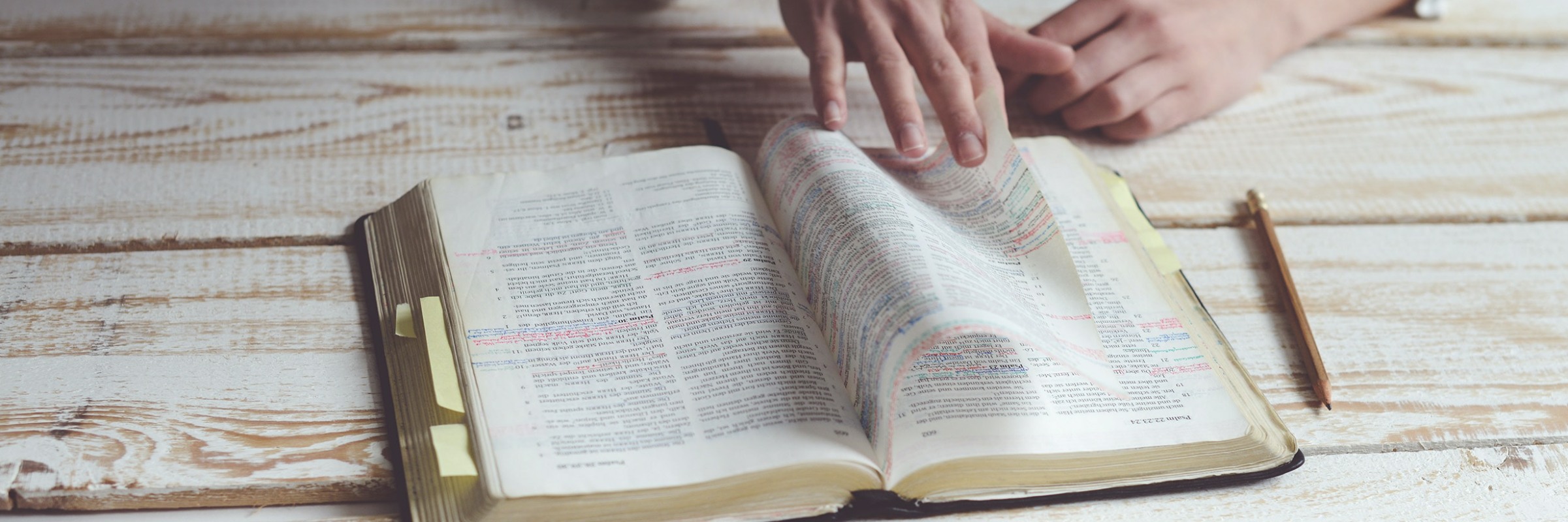 Bible being leafed through on wooden bench.