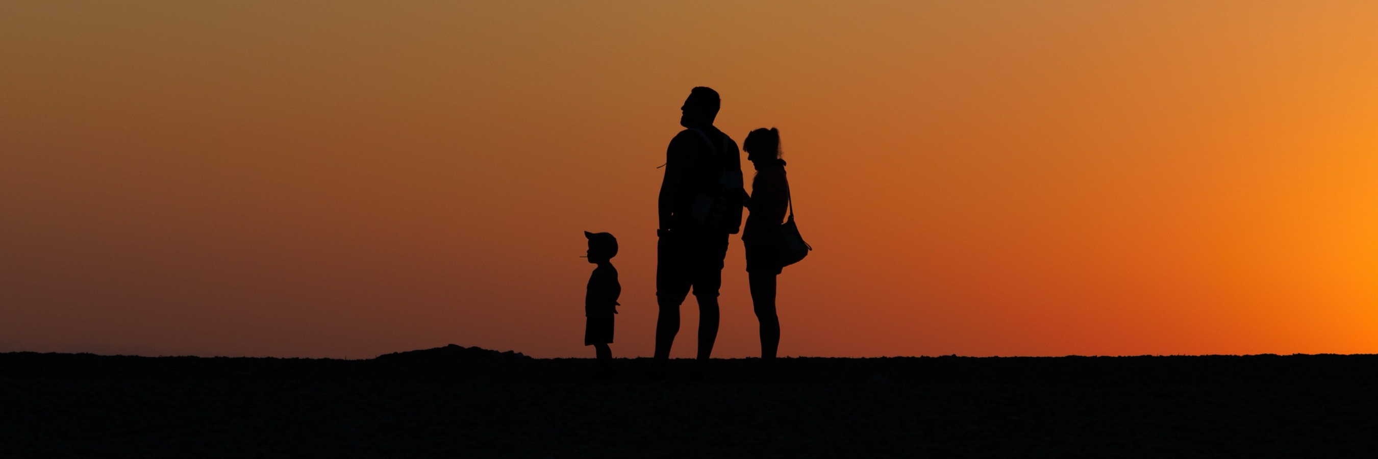 Family on horizon silhouetted by sunrise