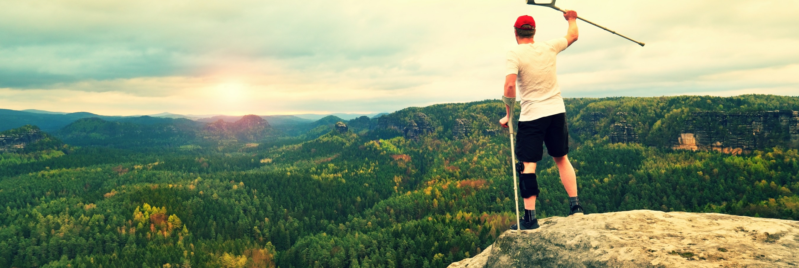 Disabled man celebrates on top of mountain.
